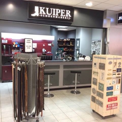 De winkel van Kuiper Schoenmakerij in De Kanaalpassage, met het zwarte uithangbord en rekken met riemen